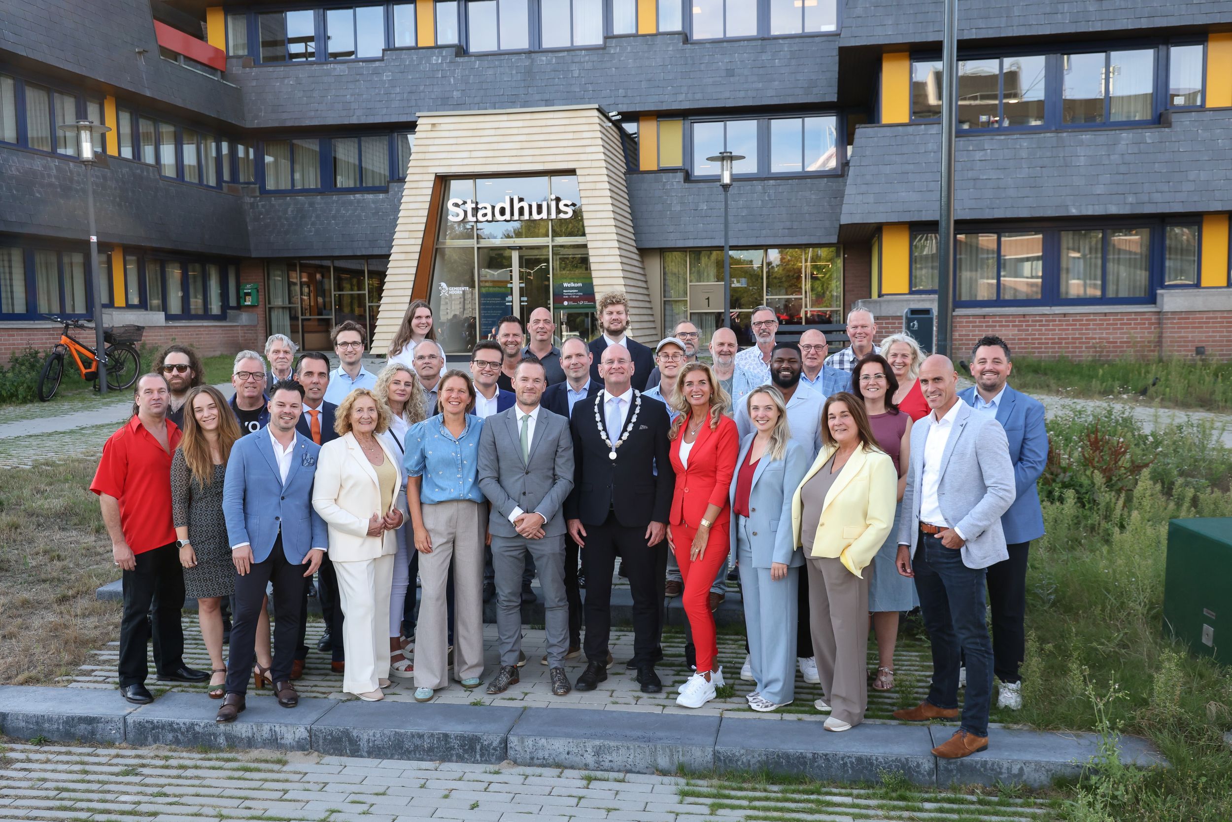 de leden van de gemeenteraad van Hoorn poseren samen met burgemeester Nieuwenburg voor het stadhuis van Hoorn