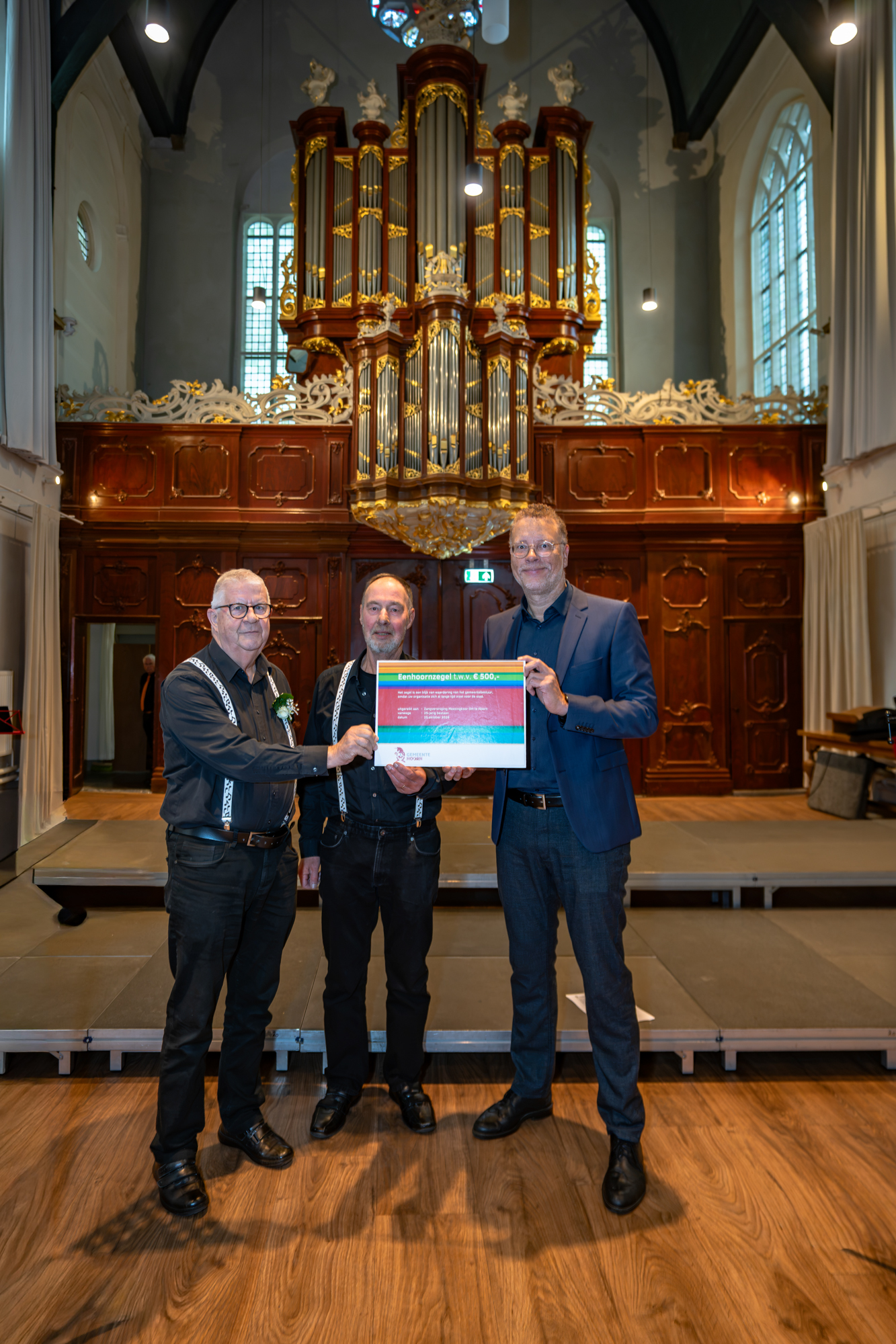 Wethouder Boutkan overhandigt het Eenhoornzegel aan Meezingkoor Om te Hoorn