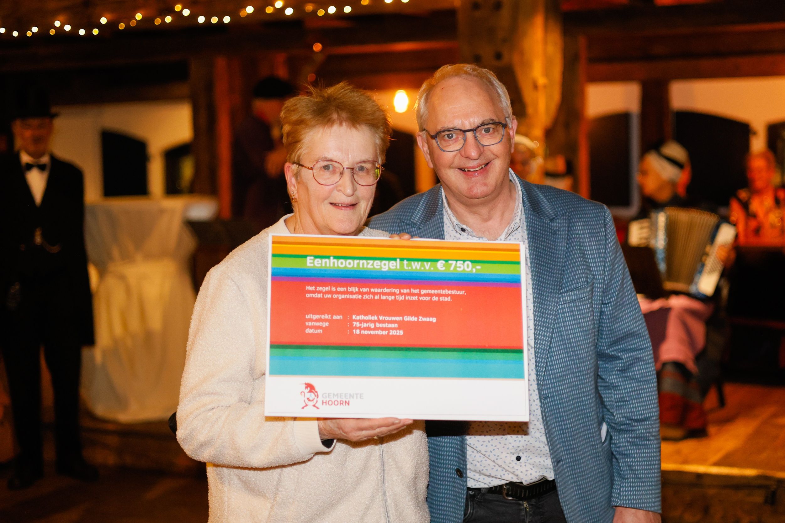 Wethouder Dick Bennis reikt het Eenhoornzegel uit aan de penningmeester van het Vrouwengilde